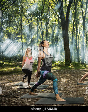 Group of youngsters keep in shape exercising in sunlight woods Stock Photo
