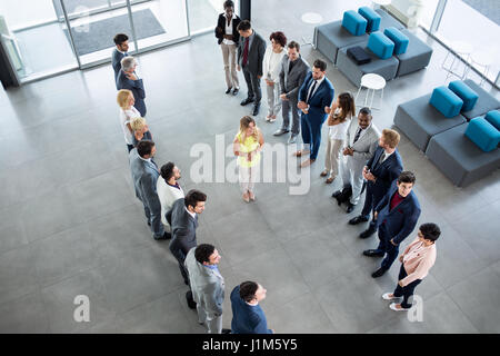 smiling young leader standing in front of his partners who applauding Stock Photo