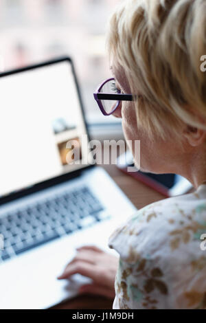 Back view of woman using laptop Stock Photo