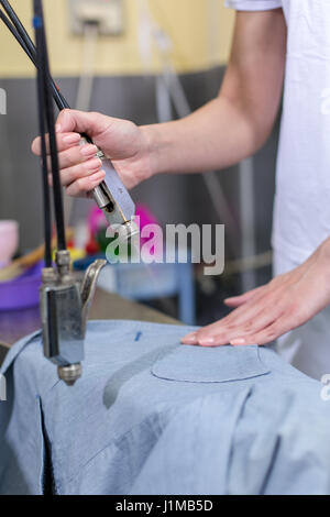 Cleaner laundry on steam cleaner in dry cleaner Stock Photo