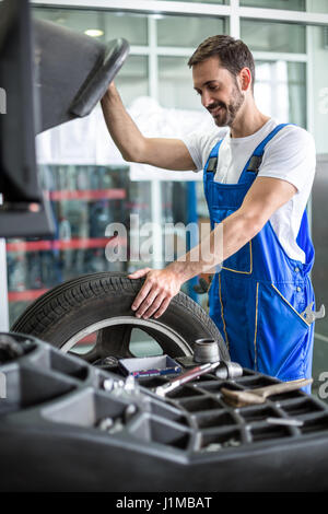 mechanic repairman installing automobile car wheel on tyre Stock Photo