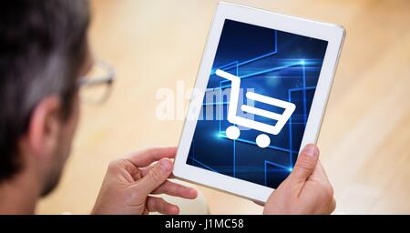 Digital composite of Man looking at shopping cart icon on digital tablet screen Stock Photo