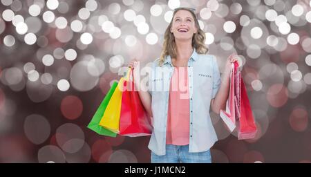 Digital composite of Woman with carrying shopping bags over bokeh Stock Photo