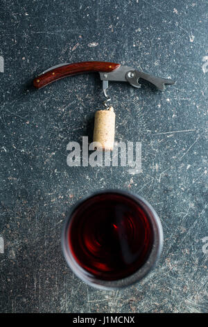 Corkscrew and red wine on old table. Stock Photo