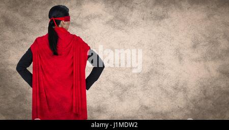 Digital composite of Back of business woman superhero with hands on hips against cream background with grunge overlay Stock Photo