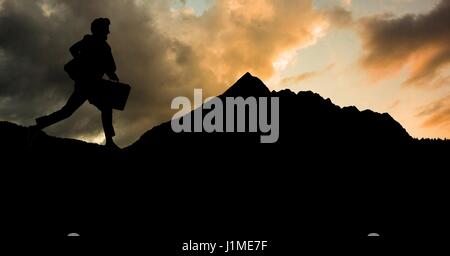 Digital composite of Silhouette businessman running on mountain against sky Stock Photo
