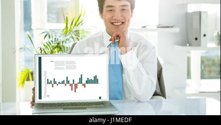 Digital composite of Portrait of businessman with graph on laptop at desk in office Stock Photo