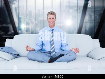 Digital composite of Business man meditating on couch against blurry dark blue window Stock Photo