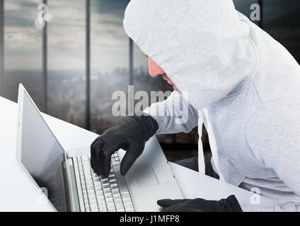 Digital composite of Criminal in hood with laptop in front of window Stock Photo