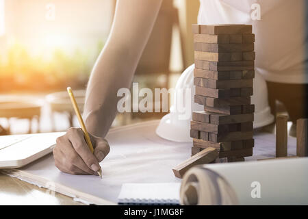 Projecting with pencil on the big urban drawings. Town planning and wood tower model for a architecture,architect working with vintage tone. Stock Photo