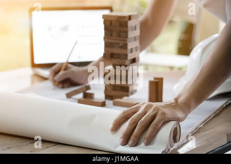 Projecting with pencil on the big urban drawings. Town planning and wood tower model for a architecture,architect working with vintage tone. Stock Photo