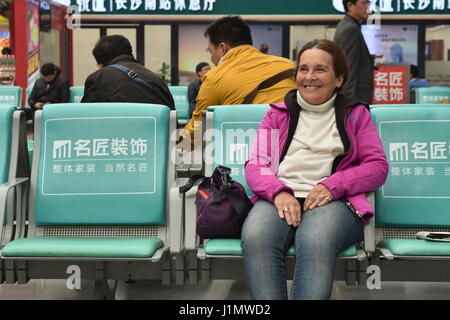 Excited smiling senior female tourist in China high-speed train station waiting area, Changsha, Hunan province Stock Photo
