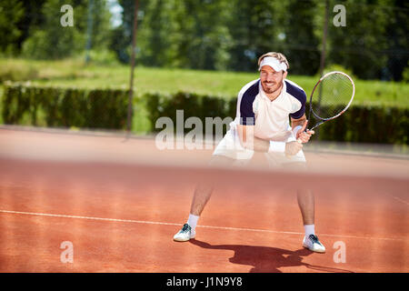 Male tennis player with racket in action on tennis court Stock Photo