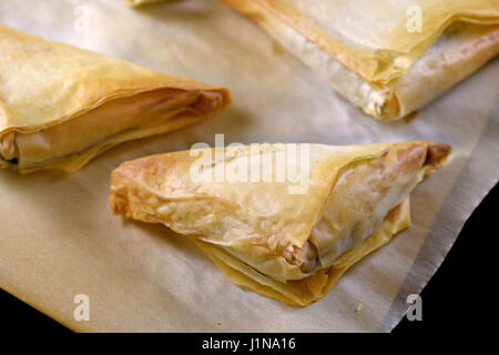 A batch of baked greek spanakopita in triangle format Stock Photo