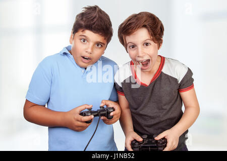 Best friends playing on playstation at home, crazy emotion of video games, two excited teen boys enjoying competition, winner and loser in the round Stock Photo