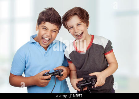 Best friends playing on playstation at home, crazy emotion of video games, two excited teen boys enjoying competition, laughing and screaming Stock Photo