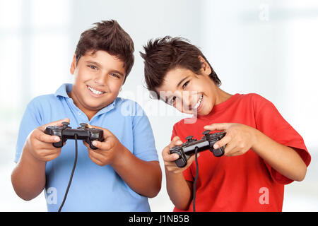 Portrait of a two cute happy boys playing video games at home, best friends enjoying competition on playstation, with pleasure having fun together Stock Photo