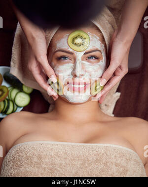 Treatment with kiwi mask on facial skin, beautiful girl in spa salon Stock Photo