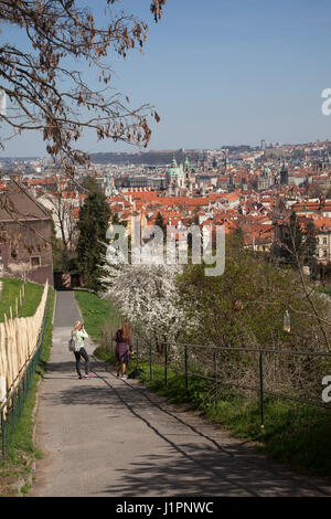 People walking along the path leading from near to the monastery in Prague down to the old town with a view over the roof tops and the river Vlatava Stock Photo