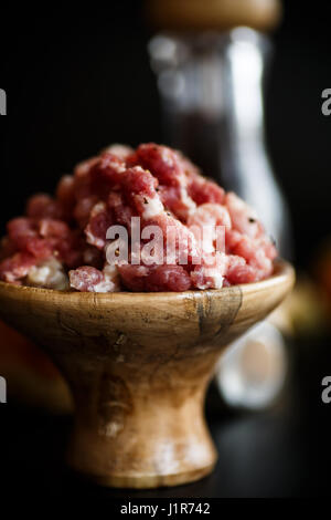 Chopped meat in a wooden bowl with spices Stock Photo