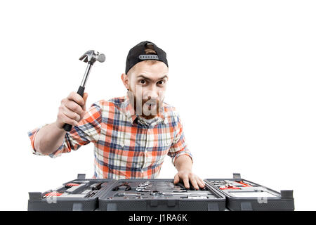 Redhead Bearded man wearing a baseball cap and shirt    holding a wrench from a toolbox in front of him. Isolated on white. Claw hammer Stock Photo