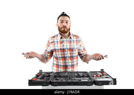 Redhead Bearded man wearing a baseball cap and shirt    holding a wrench from a toolbox in front of him. Isolated on white. MAking choose. Stock Photo