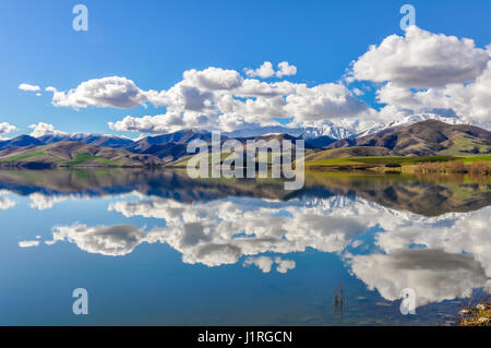 Reflection of the snowy mountains in a lake near Fairlie in the Southern Island, New Zealand Stock Photo