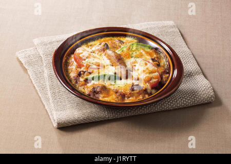Cheese cake in black bowl with saussage mushroom and vegetables Stock Photo