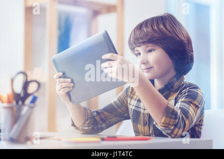 Cute boy in checked shirt looking at digital tablet Stock Photo