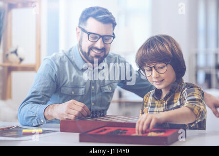 Smiling father playing chess with son Stock Photo