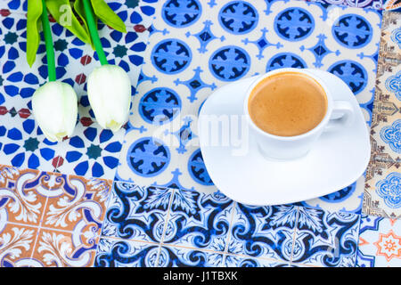 Cup of Arabian Coffee on an Oriental Colorful Background / Cup of Espresso on an Oriental Colorful Background with Flowers, Rings, and Tamr dates Stock Photo
