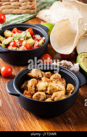 Ingredients ready for preparing chicken tacos with salsa made from avocado, tomatoes, and chilli peppers. Mexican cuisine Stock Photo