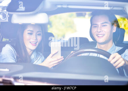 happy young asian couple using cellphone to navigate while riding a car. Stock Photo
