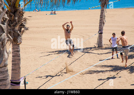 LAS PALMAS - April 15: A group pf young men practicing slacklining on Playa de Las Alcaravaneras beach, April 15, 2016 in Las Palmas, Gran Canaria, Sp Stock Photo