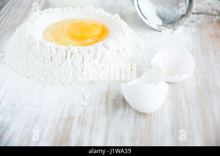 Ingredients and tools for baking - flour, eggs and glass of milk on the wooden rustic table background, selective focus. Homemade pasta preparation Stock Photo