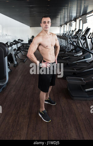 Handsome Man Standing Strong In A Modern Gym And Flexing Muscles - Muscular Athletic Bodybuilder Fitness Model Posing After Exercises Stock Photo