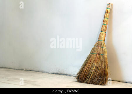 Old obsolete broom or besom leaning on the gray wall Stock Photo