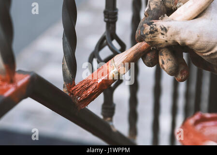 Painting forged railings on the stairs at the entrance of the house. Protection against rust. Working processes. Stock Photo