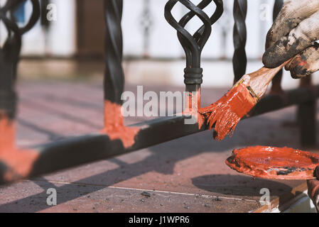 Painting forged railings on the stairs at the entrance of the house. Protection against rust. Working processes. Stock Photo