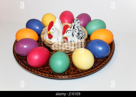 bunte Ostereier in einem Keramik-Teller mit Porzellanhühnern als Salz-und Pfefferstreuer; colored Easter eggs on a ceramic egg plate Stock Photo