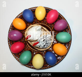 bunte Ostereier in einem Keramik-Teller mit Porzellanhühnern als Salz-und Pfefferstreuer; colored Easter eggs on a ceramic egg plate Stock Photo
