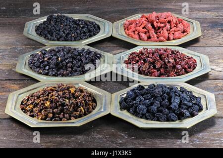 assortment of dried berries in brass bowls on wooden background Stock Photo