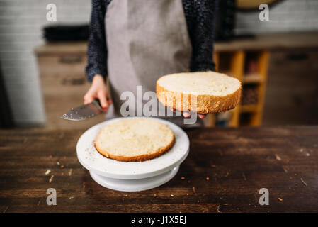 Woman cook hands holds piece of cake and knife. Homemade dessert on wooden table Stock Photo