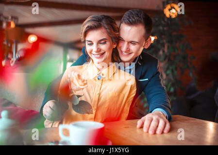 Happy man in suit gives rose to beautiful woman, romantic date in restaurant. Beautiful relationship of love couple Stock Photo