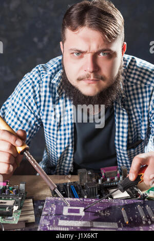 Repairman fixing problem with soldering tool. Engineer repairs computer components with soldering iron. Stock Photo