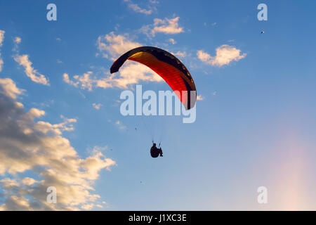 The silhouette of a person paragliding in blue sky with clouds Stock Photo