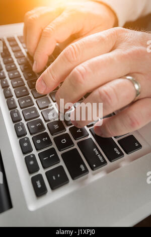 Male Hands Typing on Laptop Computer Keyboard. Stock Photo