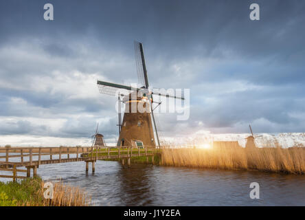 Amazing windmills at sunset. Rustic landscape with traditional dutch windmills, bridge near the water canals and blue cloudy sky. Overcast evening Stock Photo