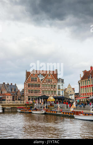 View of Graslei (Grass Quay) with medieval buildings and unidentified tourists on a cloudy day. Ghent, Belgium. Stock Photo