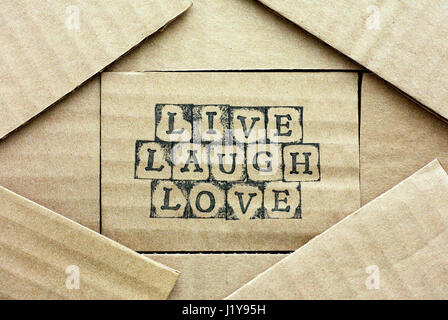 Cardboard card with words Live Laugh Love made by black alphabet stamps with piece of cardboard. Stock Photo